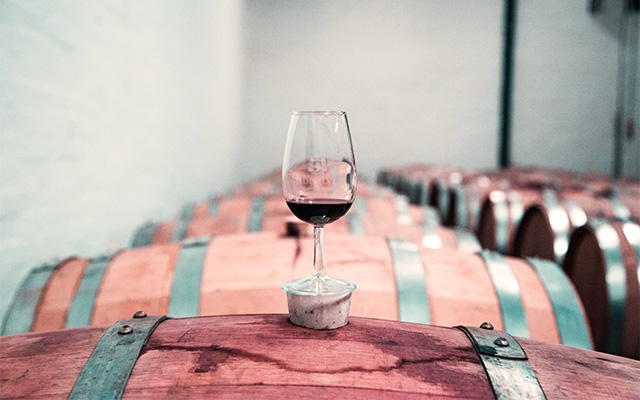 Glass of red wine perched on a wine barrel